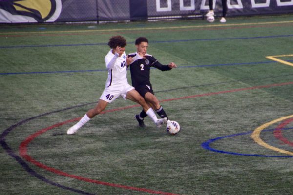 Number 40, Louis Hawkins, tries to keep the ball away from Curry College player. 